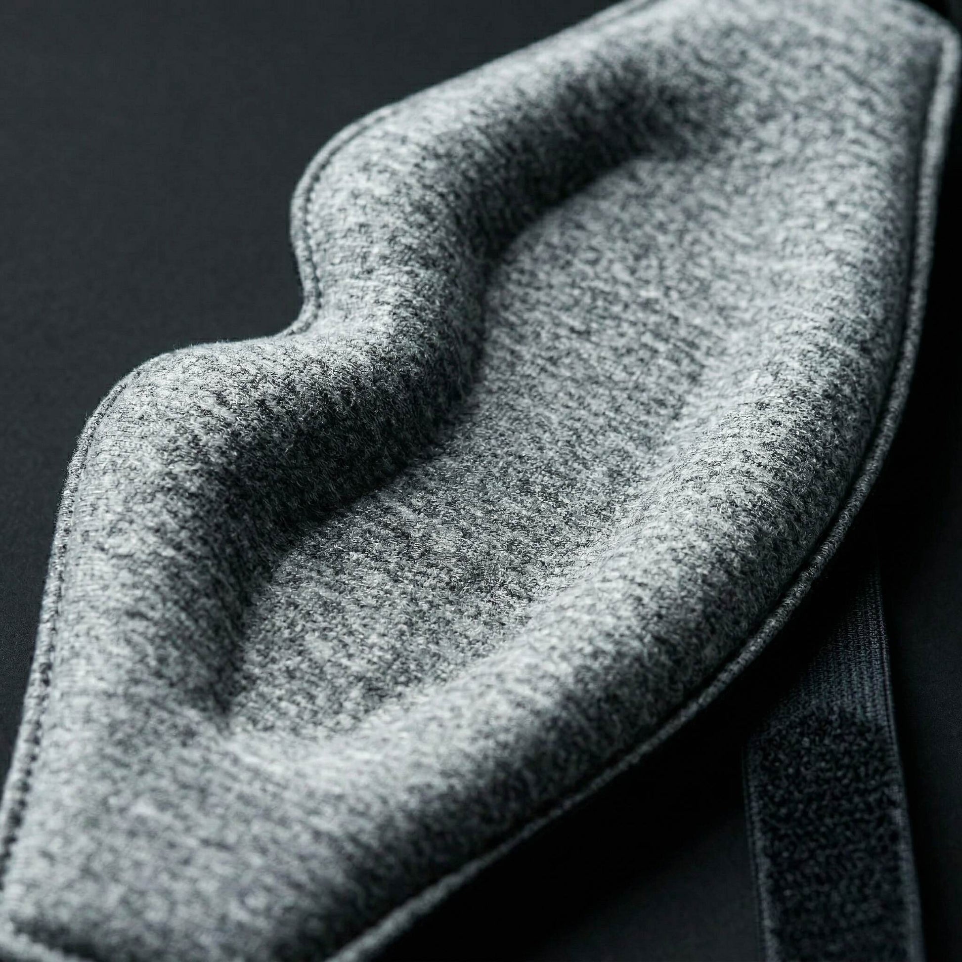 Close-up of a textured gray fabric of sleep eye mask with a dark background